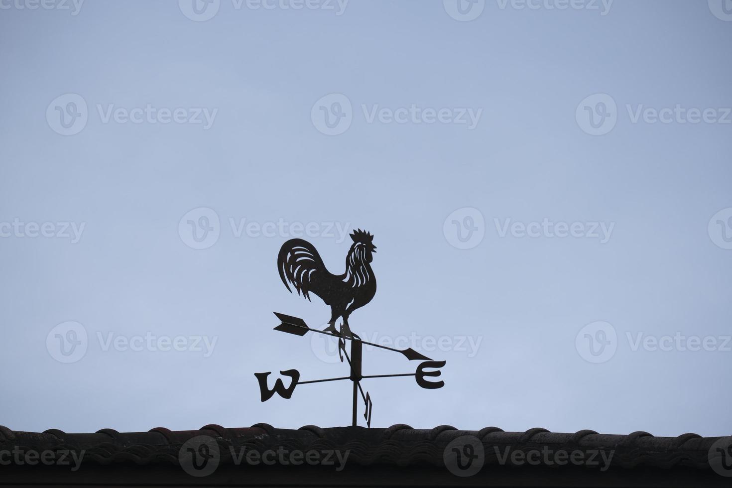 il vecchio vento banderuola con un' Gallo simbolo icona su il tetto, tradizionale tecnologia attrezzatura per previsione e misurazione ventoso tempo metereologico nel il aria, Vintage ▾ decorazione, mirando vento direzione strumento. foto