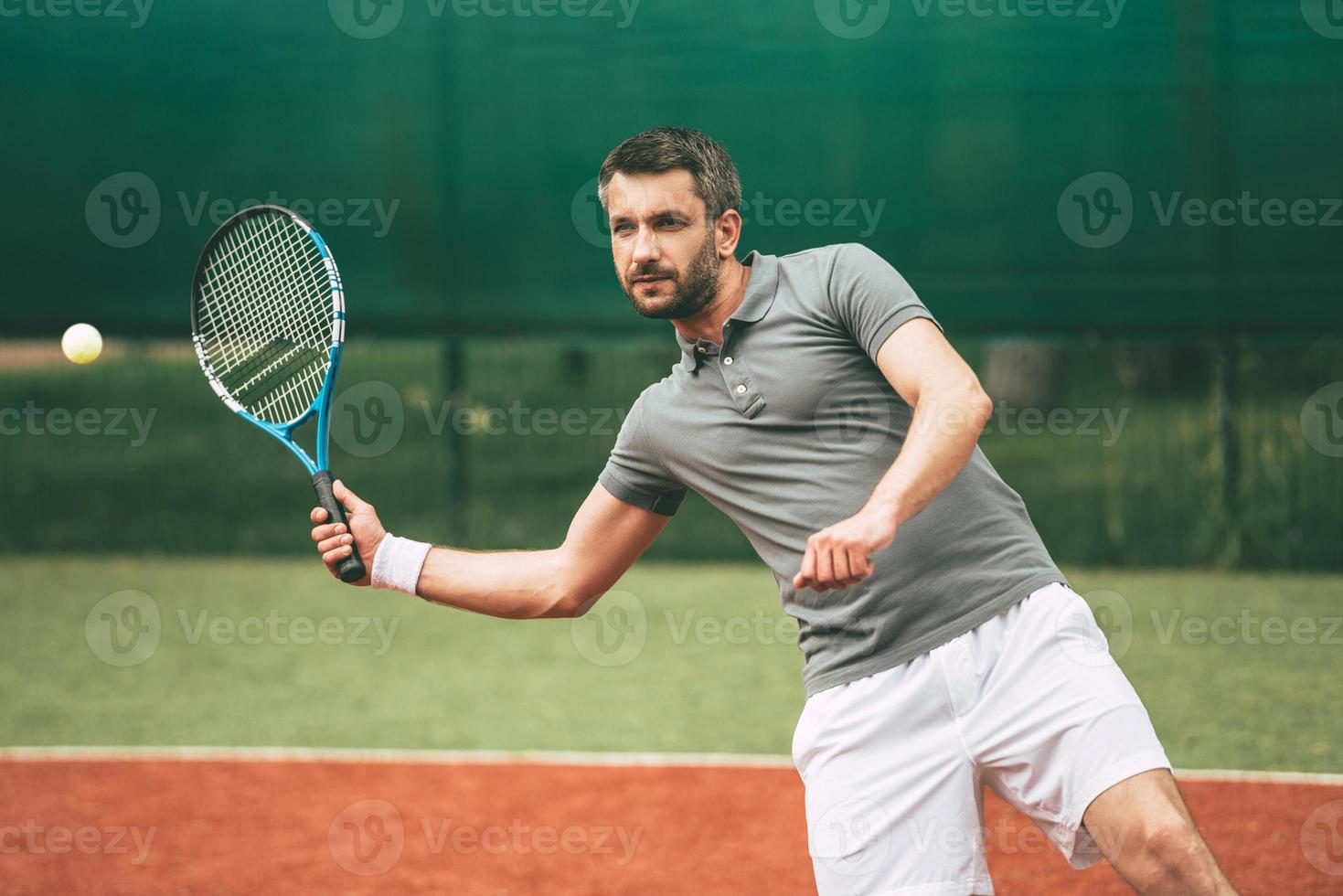 fiducioso tennis giocatore. fiducioso giovane uomo nel gli sport Abiti giocando tennis su tennis Tribunale foto