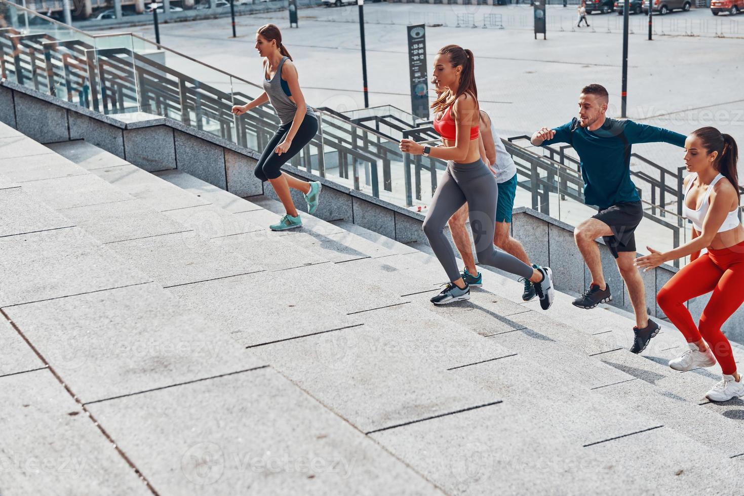 gruppo di giovane persone nel gli sport capi di abbigliamento jogging mentre esercizio su il le scale all'aperto foto