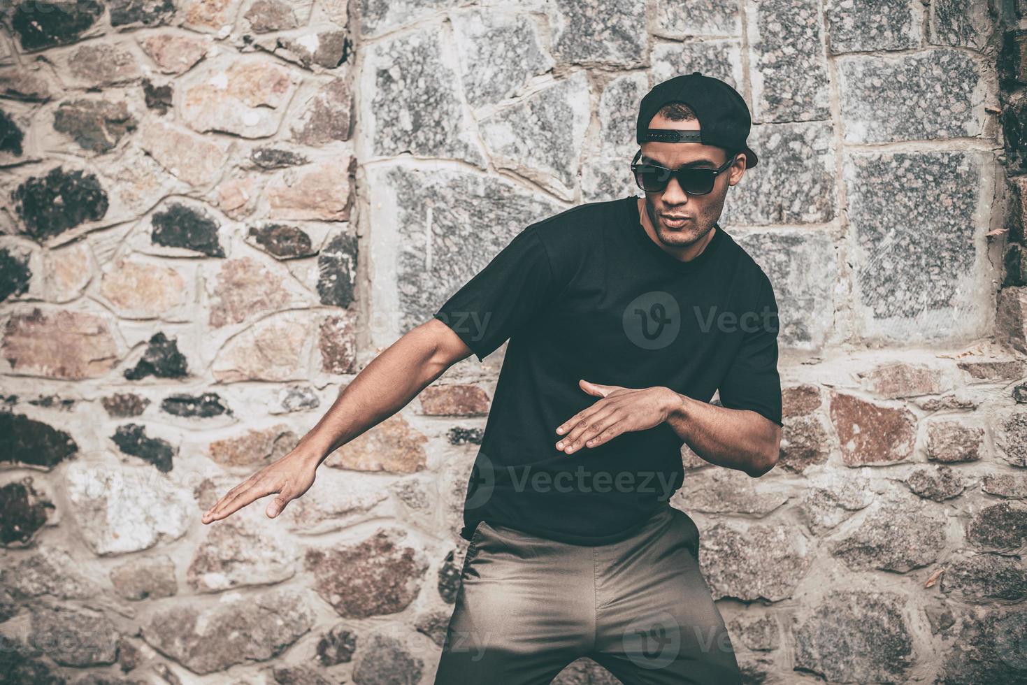 soggiorno freddo. bello giovane africano uomo nel casuale Abiti danza contro il sballato parete all'aperto foto