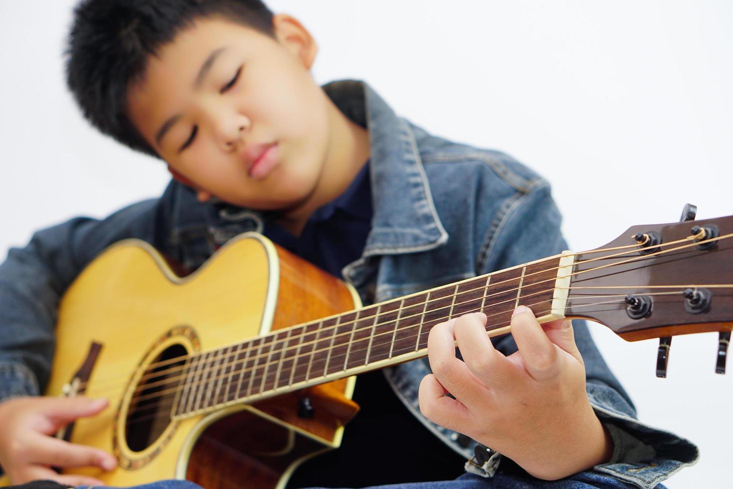 messa a fuoco su il mani di il bambino o adolescente giocando acustico chitarra su bianca sfondo. apprendimento e rilassare concetto. foto