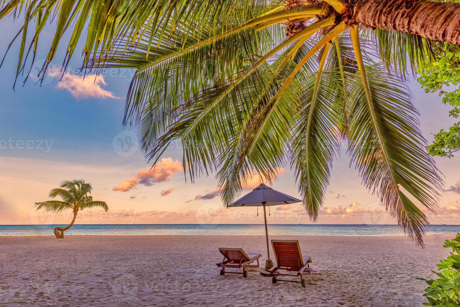 bellissimo tropicale tramonto paesaggio, romantico sedie, lettini ombrello sbalorditivo palma albero. bianca sabbia, mare Visualizza orizzonte, colorato crepuscolo cielo, quiete e rilassamento. sorprendente coppia spiaggia ricorrere foto