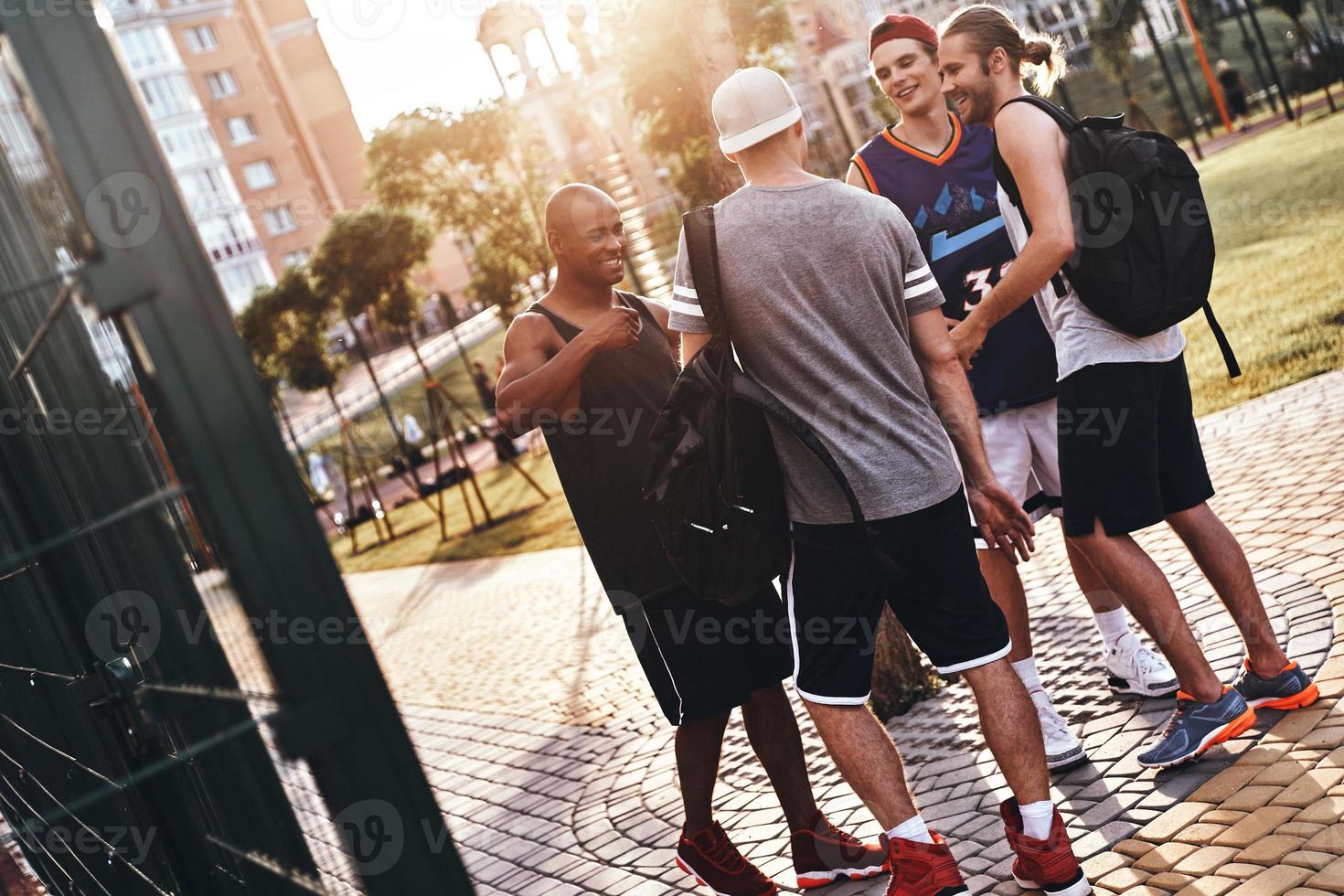 grande giorno con gli amici. gruppo di giovane uomini nel gli sport capi di abbigliamento sorridente mentre in piedi all'aperto foto