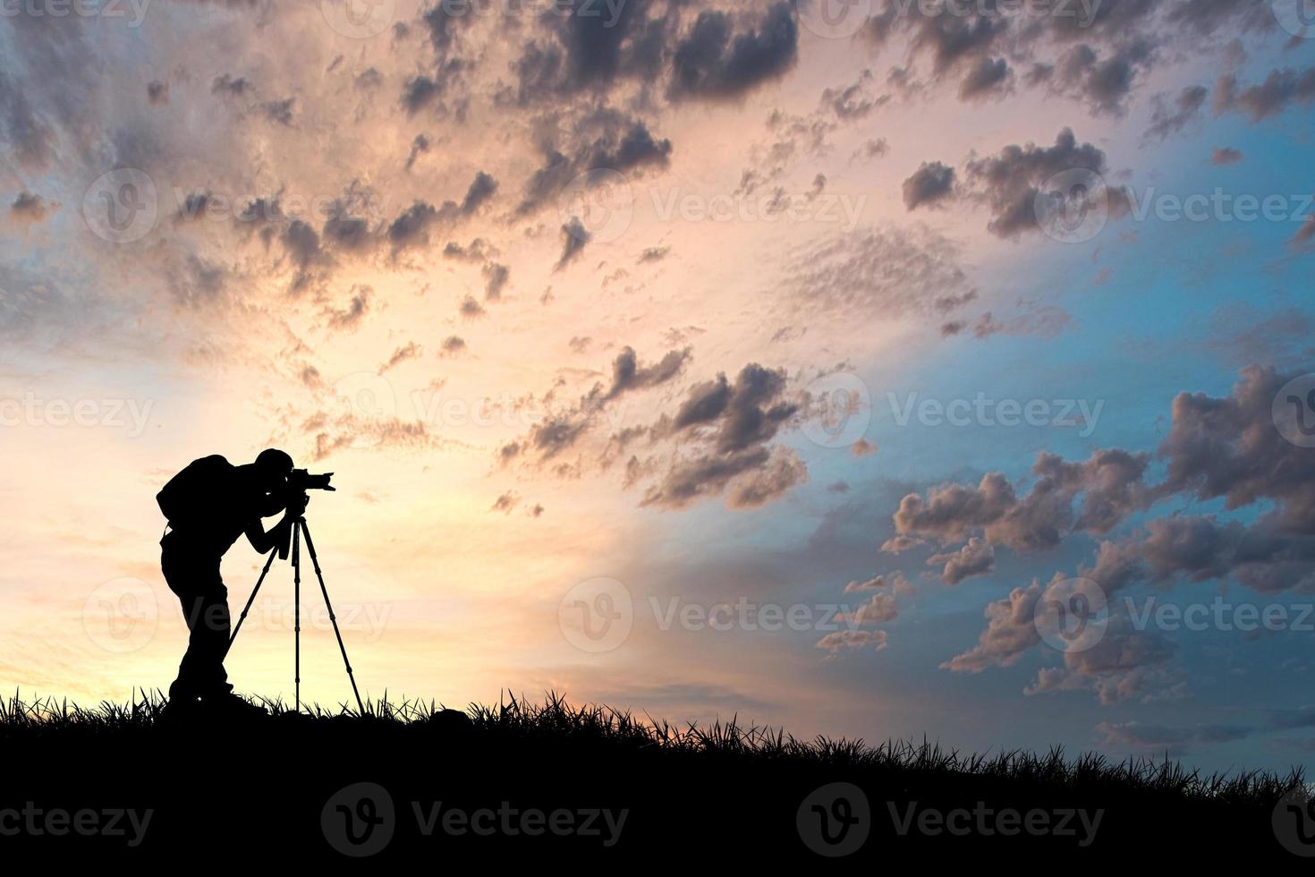 la silhouette di un fotografo professionista è focalizzata sullo scatto in un bellissimo prato. foto