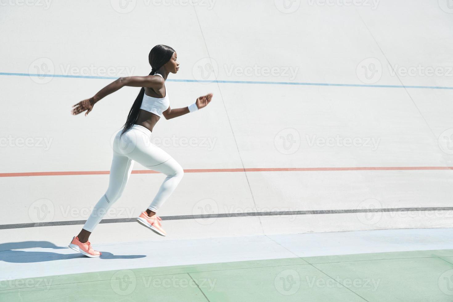 bellissimo giovane africano donna nel gli sport capi di abbigliamento in esecuzione su traccia all'aperto foto