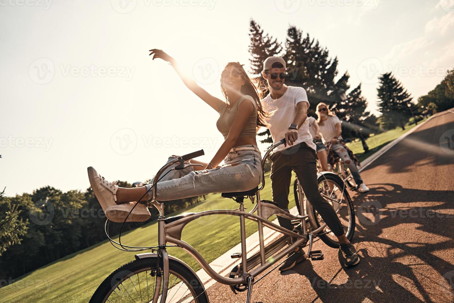 godendo il momento. gruppo di contento giovane persone nel casuale indossare sorridente mentre Ciclismo insieme all'aperto foto