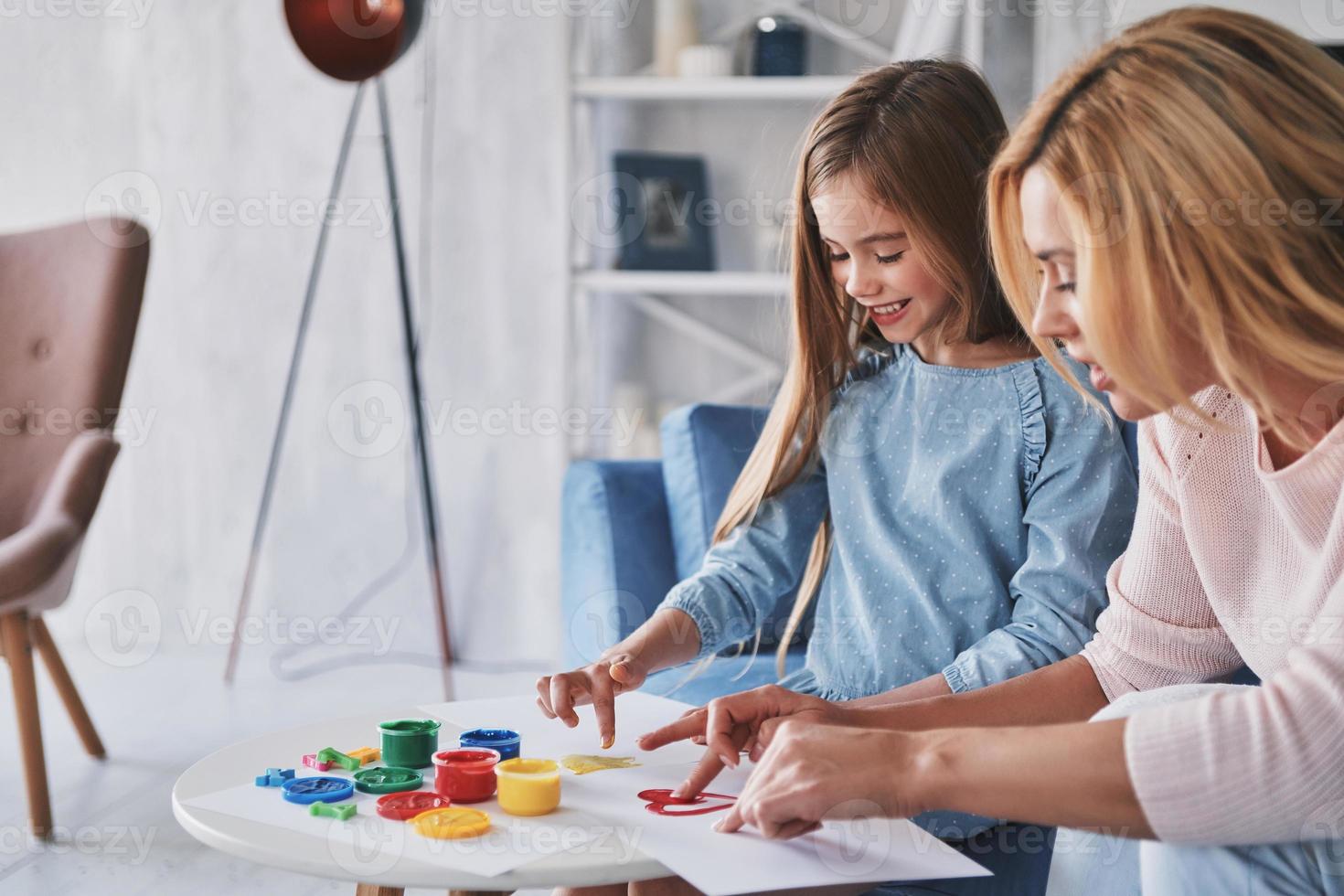 godendo disegno insieme. madre e figlia pittura con dita e sorridente mentre la spesa tempo a casa foto