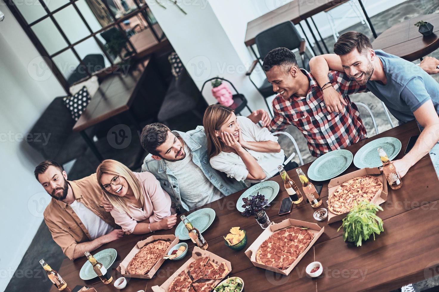 contento per essere intorno a. superiore Visualizza di giovane persone nel casuale indossare parlando e sorridente mentre avendo un' cena festa nel il ristorante foto