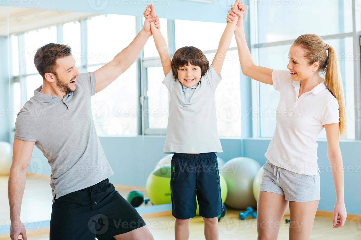 contento per essere sano. contento padre e madre avendo divertimento con loro figlio nel Salute club con fitness palle posa nel il sfondo foto