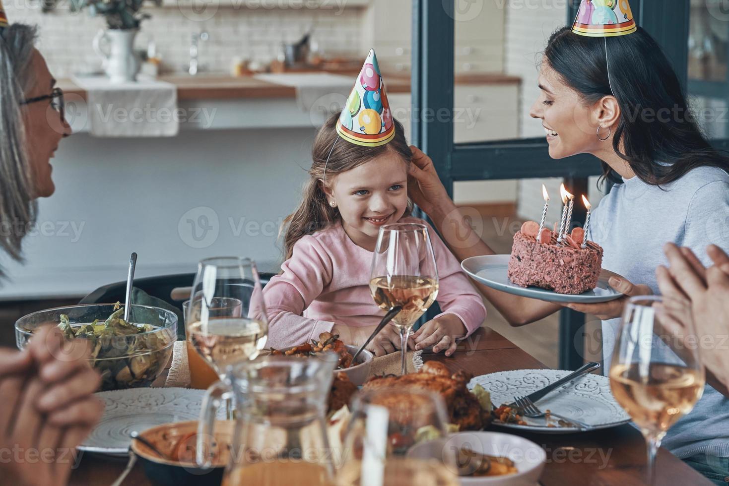 contento famiglia festeggiare compleanno di poco ragazza mentre seduta a il cenare tavolo a casa foto