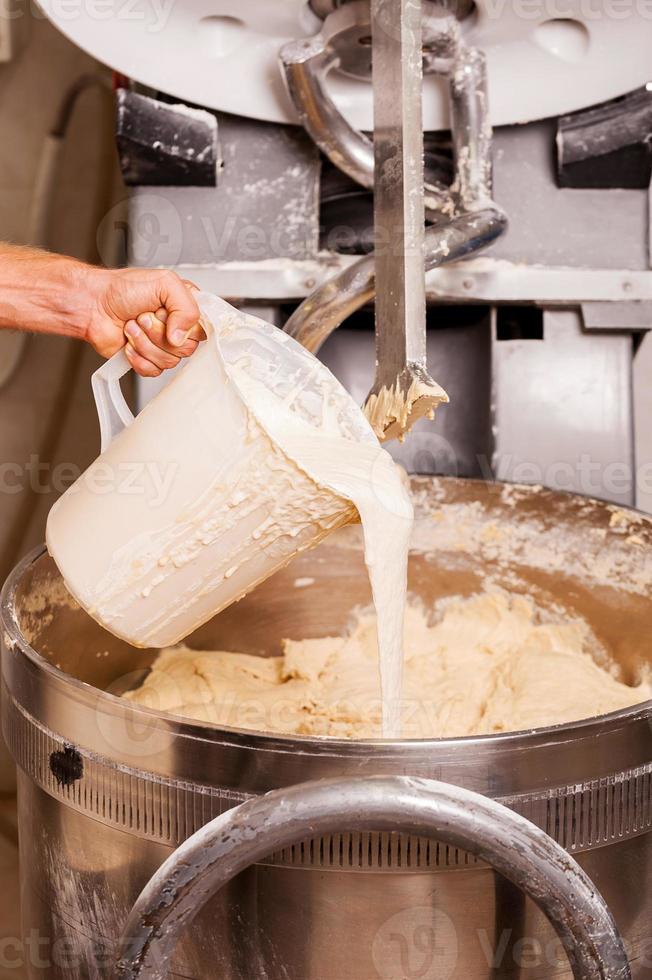 preparazione Impasto. avvicinamento di uomo porsi ingredienti in il Impasto miscelazione macchina foto