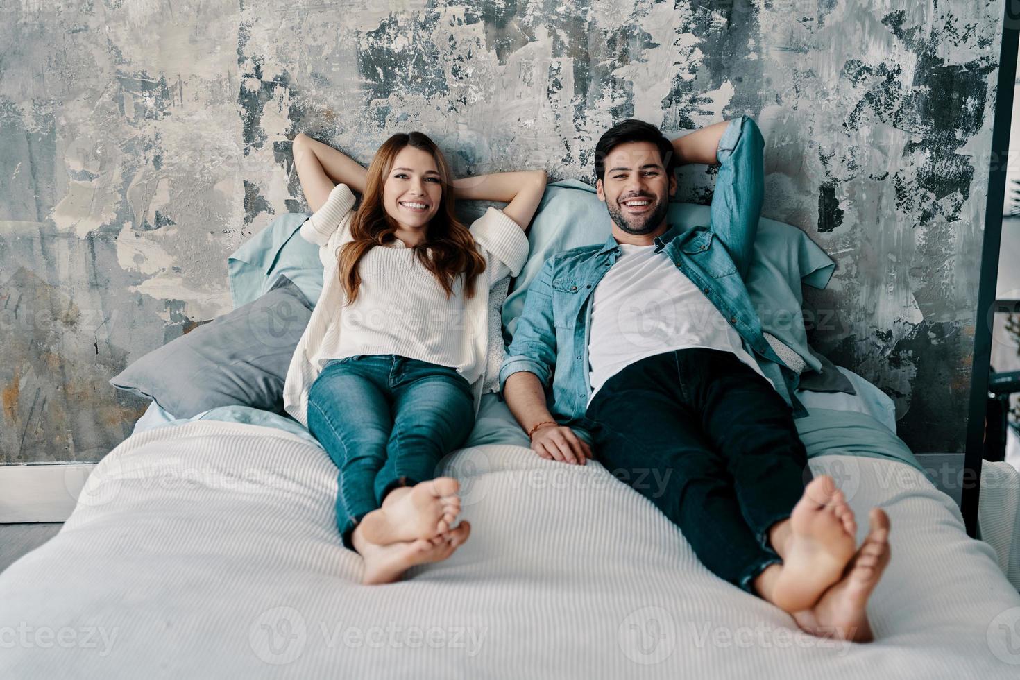 Perfetto coppia. bellissimo giovane coppia guardare a telecamera e sorridente mentre la spesa tempo nel letto a casa foto
