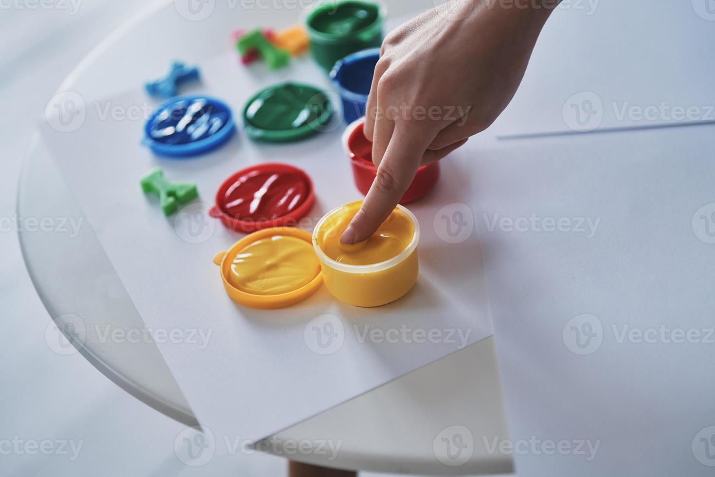 godendo la pittura. vicino su superiore Visualizza di poco ragazza toccante vernici mentre la spesa tempo a casa foto