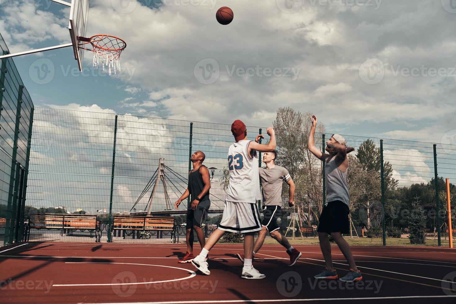 tiro a obiettivo. gruppo di giovane uomini nel gli sport capi di abbigliamento giocando pallacanestro mentre la spesa tempo all'aperto foto