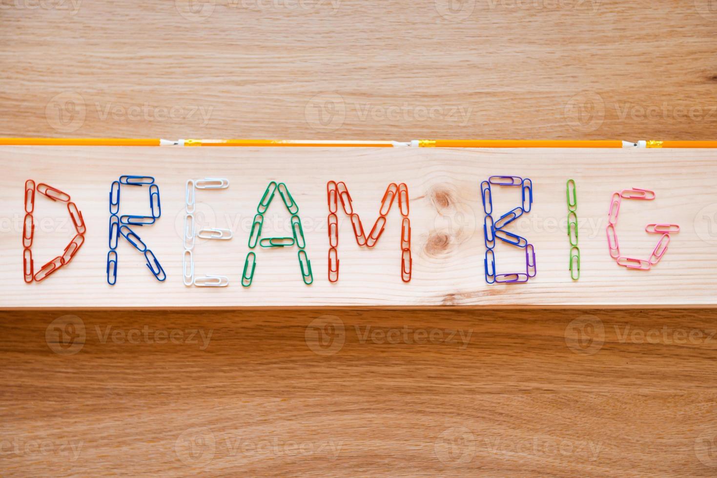 sognare grande. superiore Visualizza di sognare grande testo fatto a partire dal colorato graffette posa su il legna grano foto
