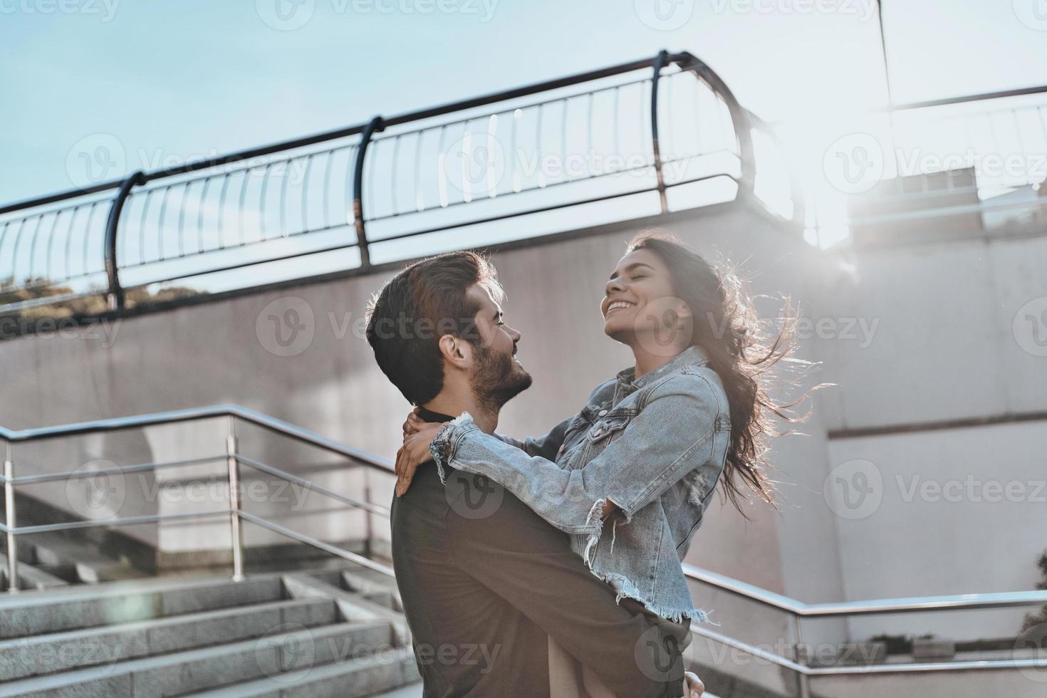 amore è nel il aria. bello uomo trasporto giovane attraente donna mentre la spesa tempo all'aperto foto