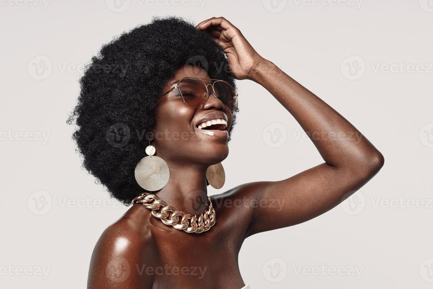 bellissimo giovane africano donna nel d'oro gioielleria conservazione occhi chiuso e sorridente foto