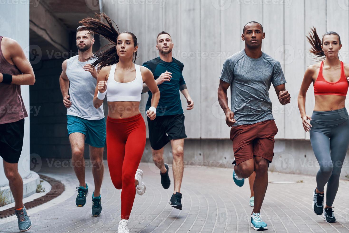 gruppo di giovane persone nel gli sport capi di abbigliamento jogging mentre esercizio all'aperto foto