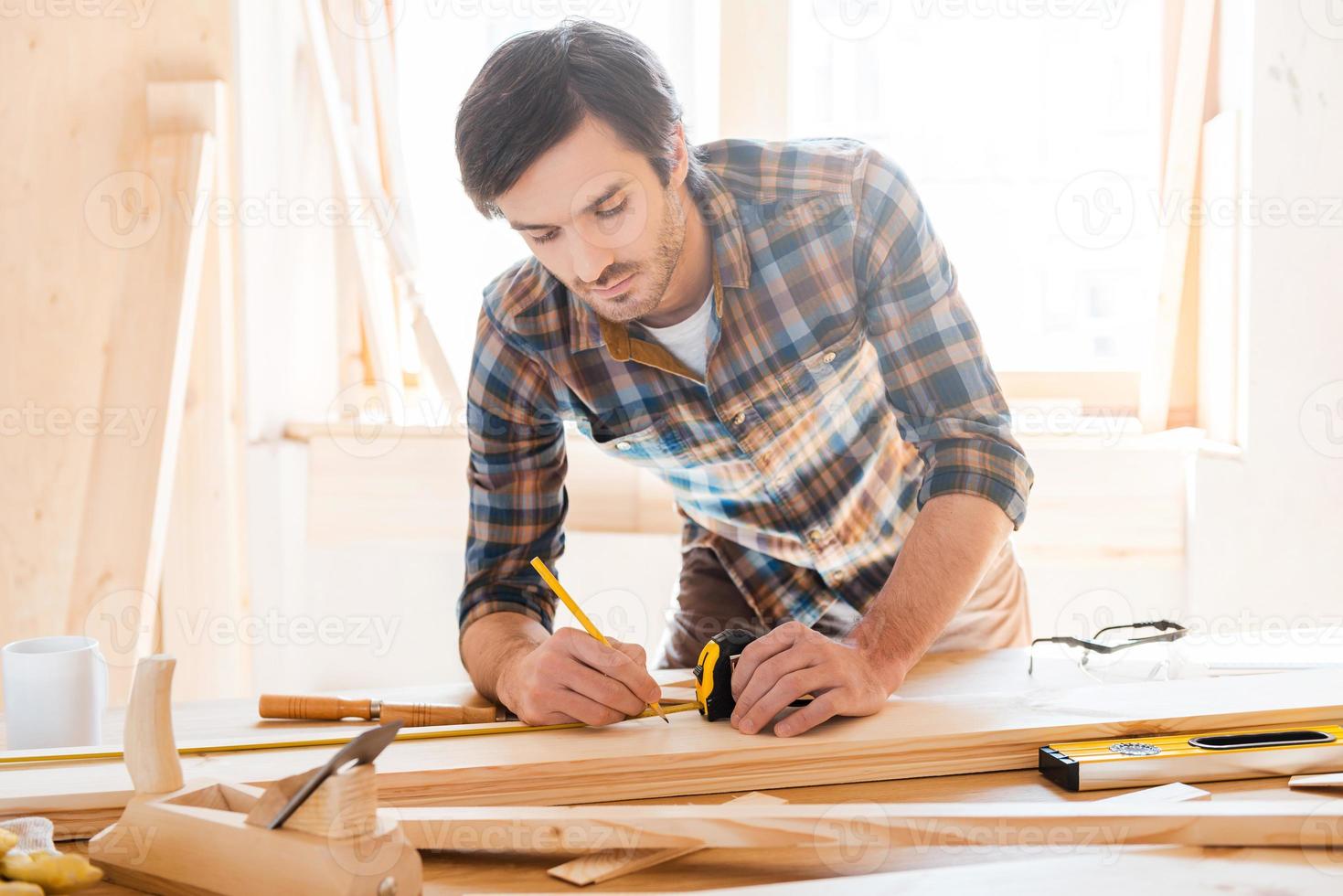 precisione per tutto. grave giovane maschio falegname Lavorando con legna nel il suo laboratorio foto