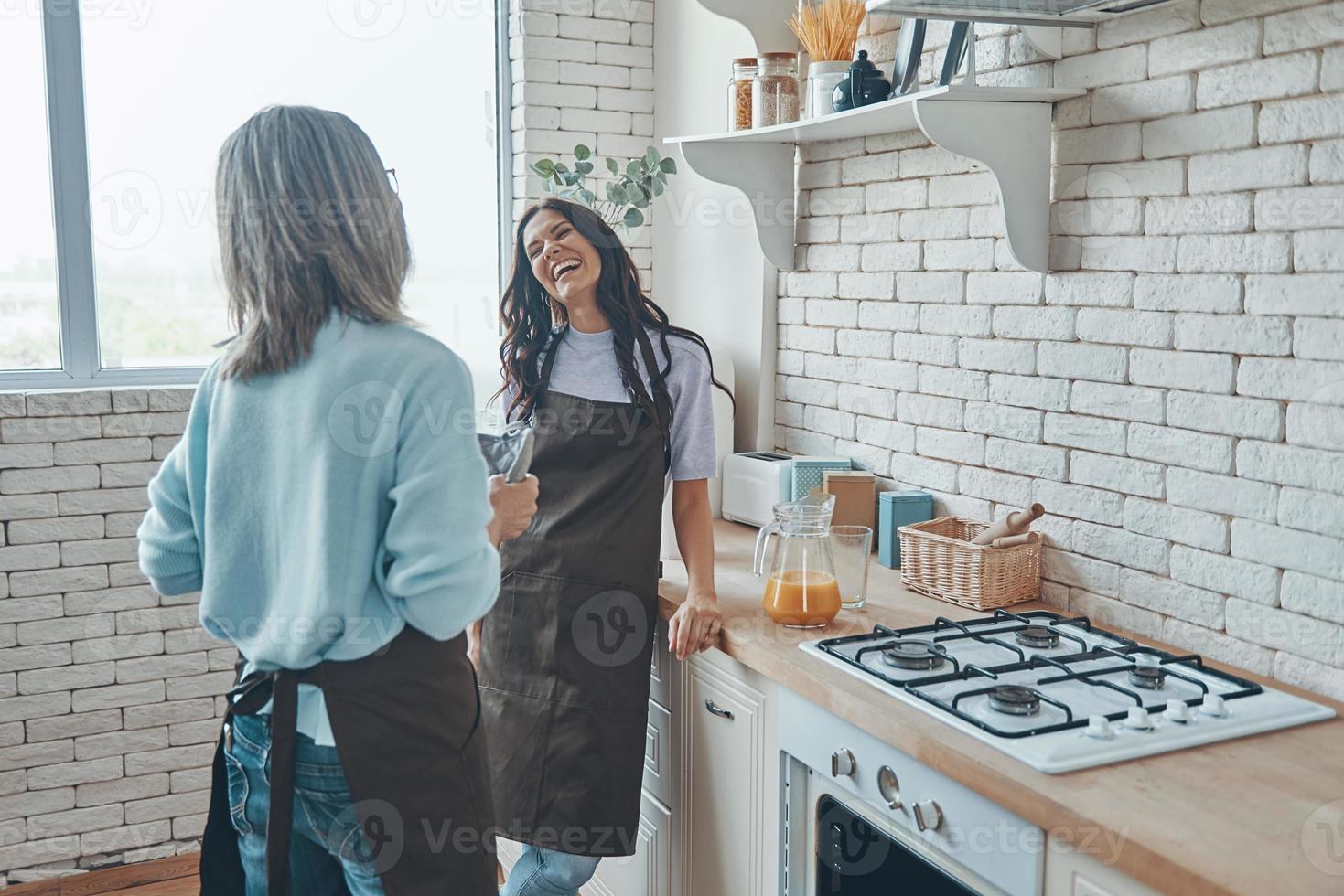 bellissimo giovane donna e sua madre comunicare mentre la spesa tempo a il domestico cucina foto