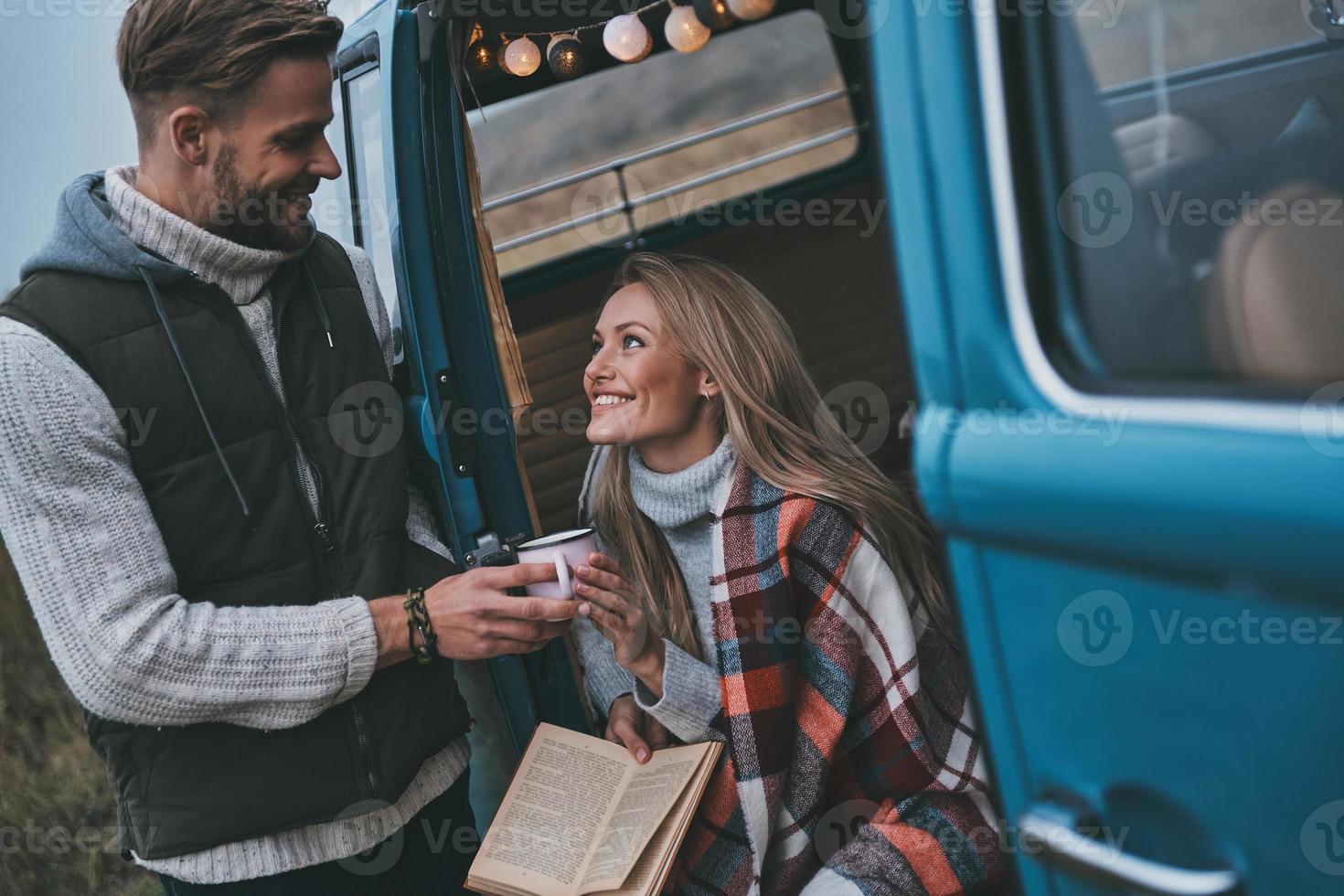 caldo tè per suo. bello giovane uomo dando un' boccale per il suo fidanzata mentre godendo loro strada viaggio foto
