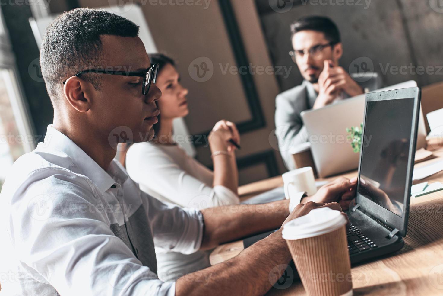 concentrato a opera. gruppo di giovane moderno persone nel inteligente casuale indossare Lavorando mentre seduta nel il creativo ufficio foto