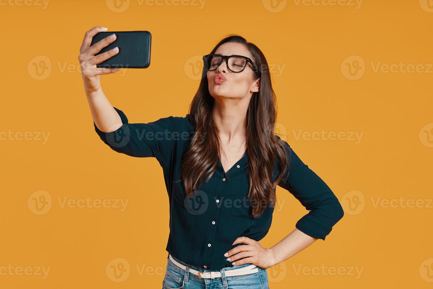 contento giovane donna nel casuale capi di abbigliamento assunzione autoscatto e increspando foto