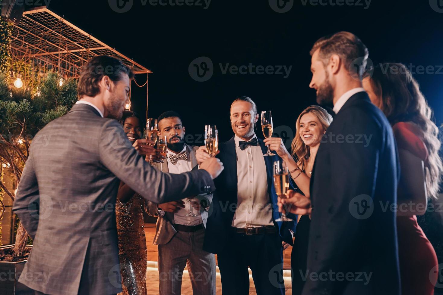 gruppo di bellissimo persone nel vestito formale tostatura con Champagne e sorridente mentre la spesa tempo su lusso festa foto