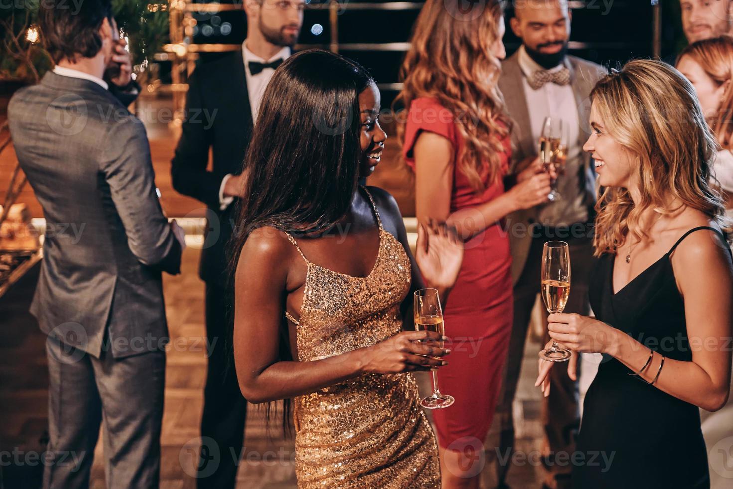 gruppo di bellissimo giovane persone nel vestito formale comunicare e sorridente mentre la spesa tempo su lusso festa foto