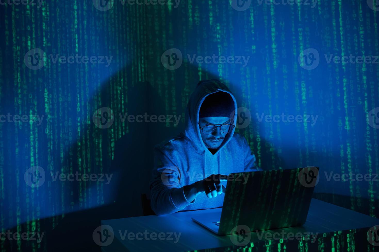 giovane uomo nel incappucciato camicia utilizzando computer contro buio sfondo foto