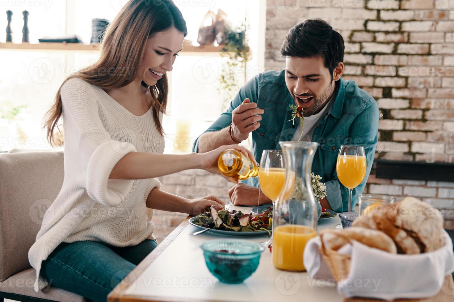 bene pasto nel un' bene azienda. bellissimo giovane coppia godendo salutare prima colazione mentre seduta nel il cucina a casa foto