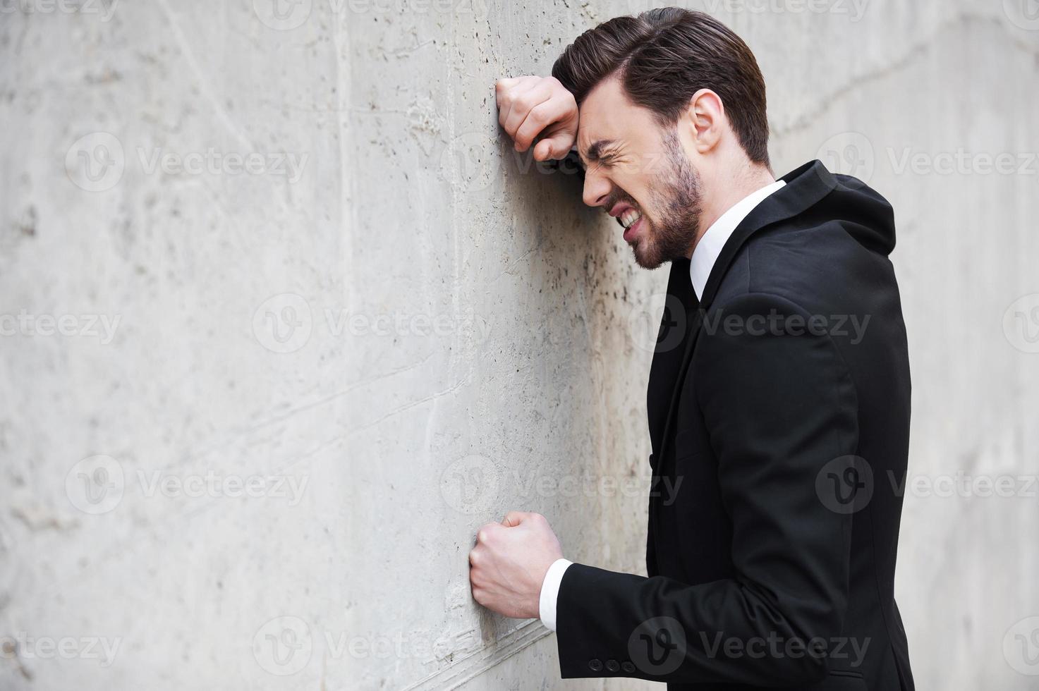 depresso uomo d'affari. lato Visualizza di depresso giovane uomo nel camicia e cravatta pendente a il parete e conservazione occhi chiuso foto