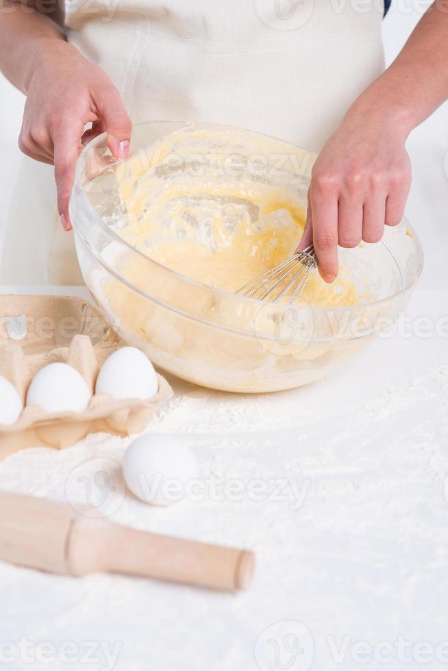 fabbricazione fatti in casa Pasticcino. avvicinamento di donna miscelazione Impasto nel un' miscelazione ciotola foto