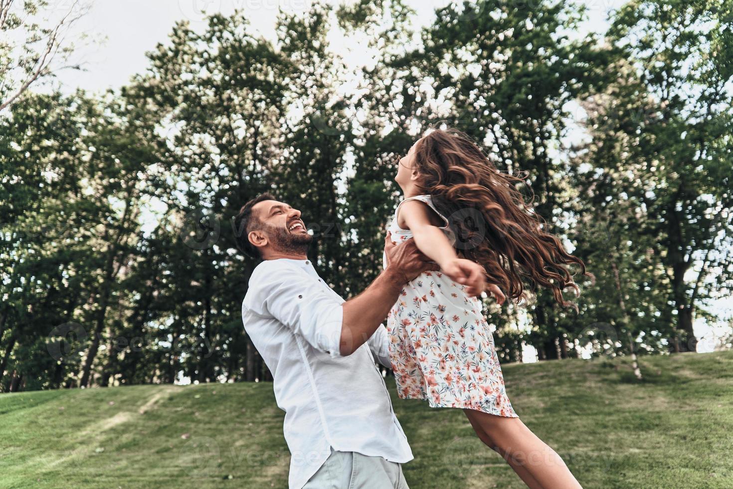 lui è sempre Là per suo. giovane amorevole padre trasporto il suo figlia e sorridente mentre la spesa gratuito tempo all'aperto foto