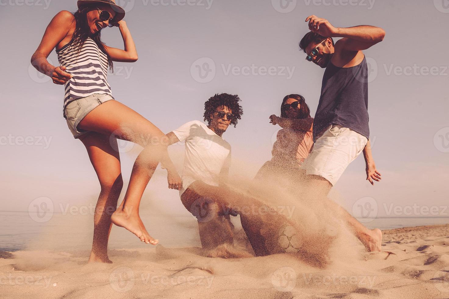 il mio gruppo di allegro giovane persone giocando con calcio palla su il spiaggia foto