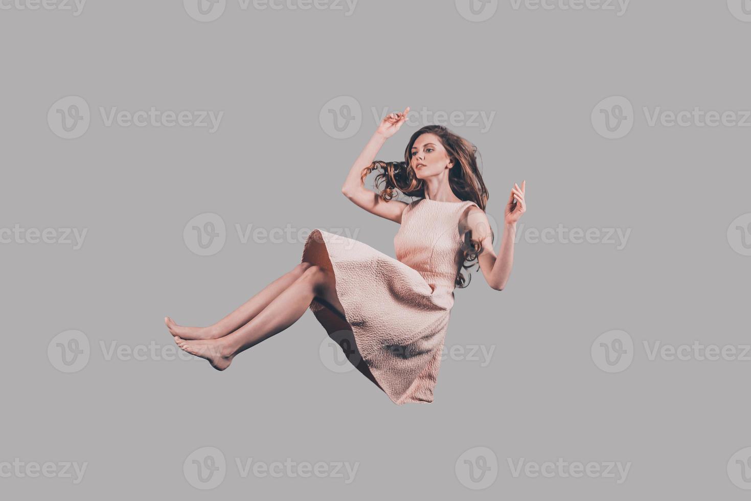 bellezza nel movimento. studio tiro di attraente giovane donna librarsi nel aria foto