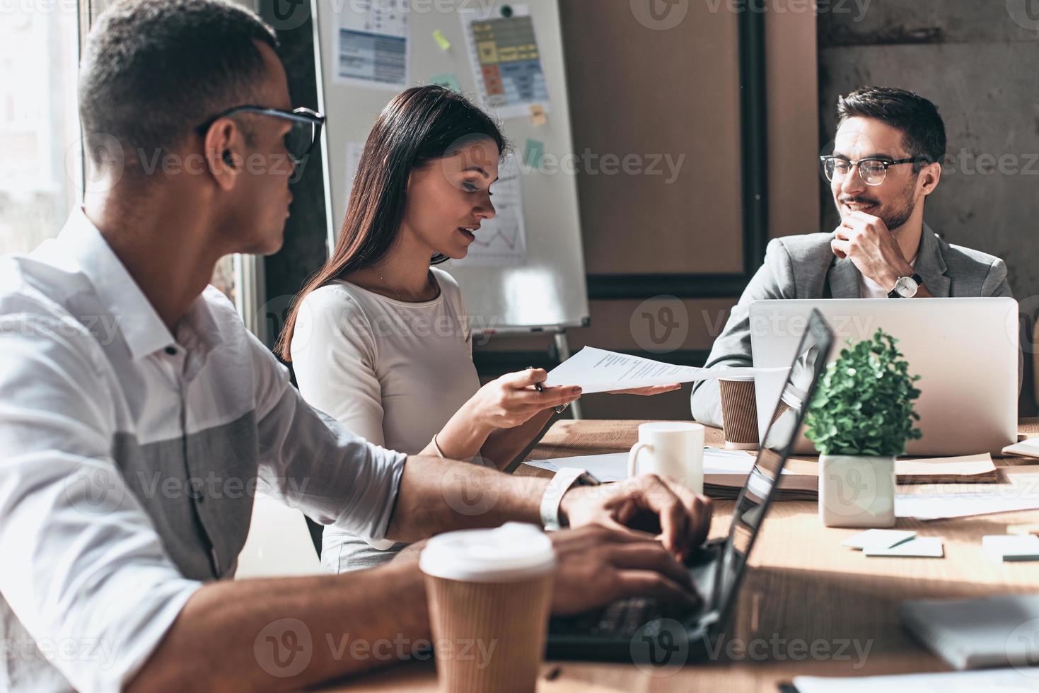 discutere strategia. gruppo di giovane moderno persone nel inteligente casuale indossare discutere attività commerciale mentre seduta nel il creativo ufficio foto