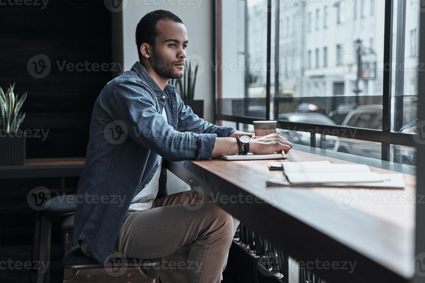 ricerca per ispirazione. riflessivo giovane uomo guardare attraverso il finestra mentre seduta nel il caffetteria foto