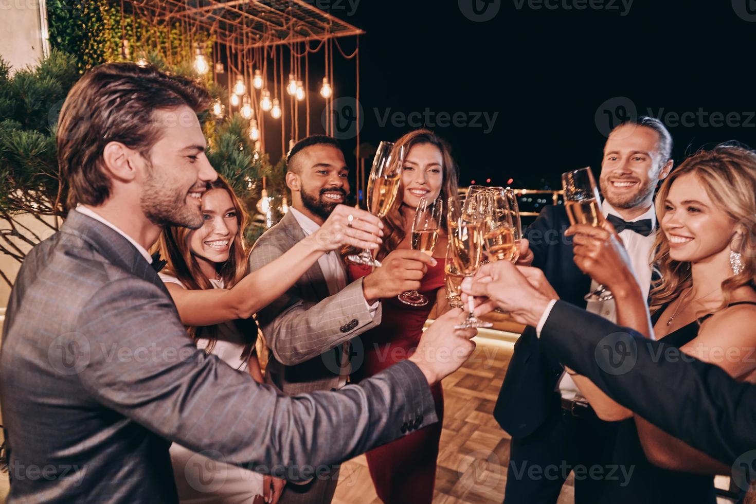 gruppo di bellissimo persone nel vestito formale tostatura con Champagne e sorridente mentre la spesa tempo su lusso festa foto