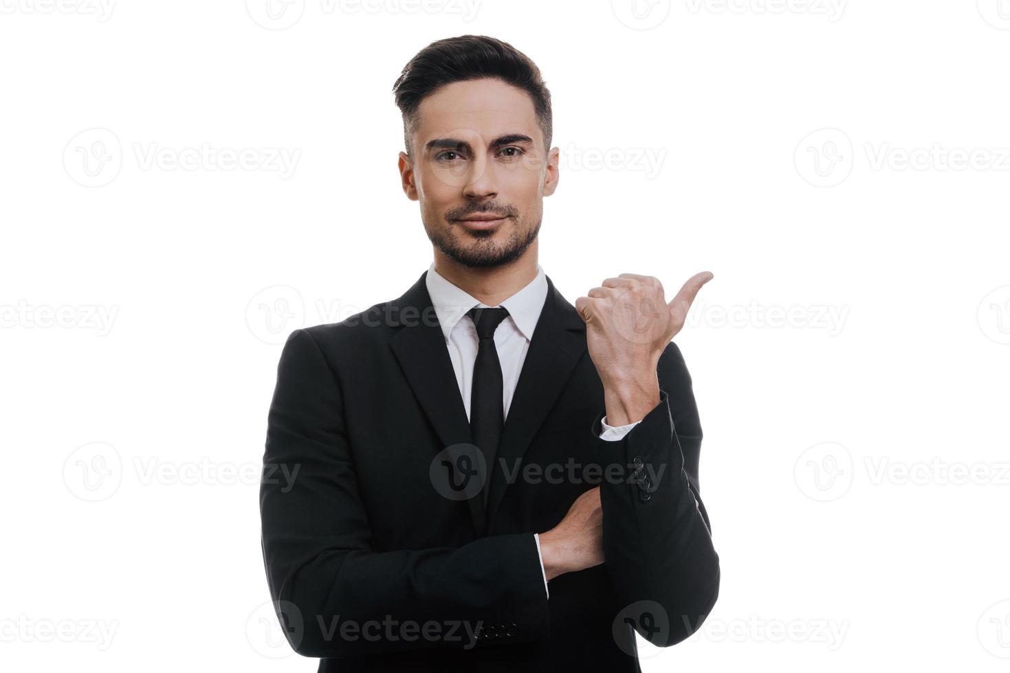 Guarda a Questo bene guardare giovane uomo nel pieno completo da uomo puntamento lontano e sorridente per voi mentre in piedi contro bianca sfondo foto