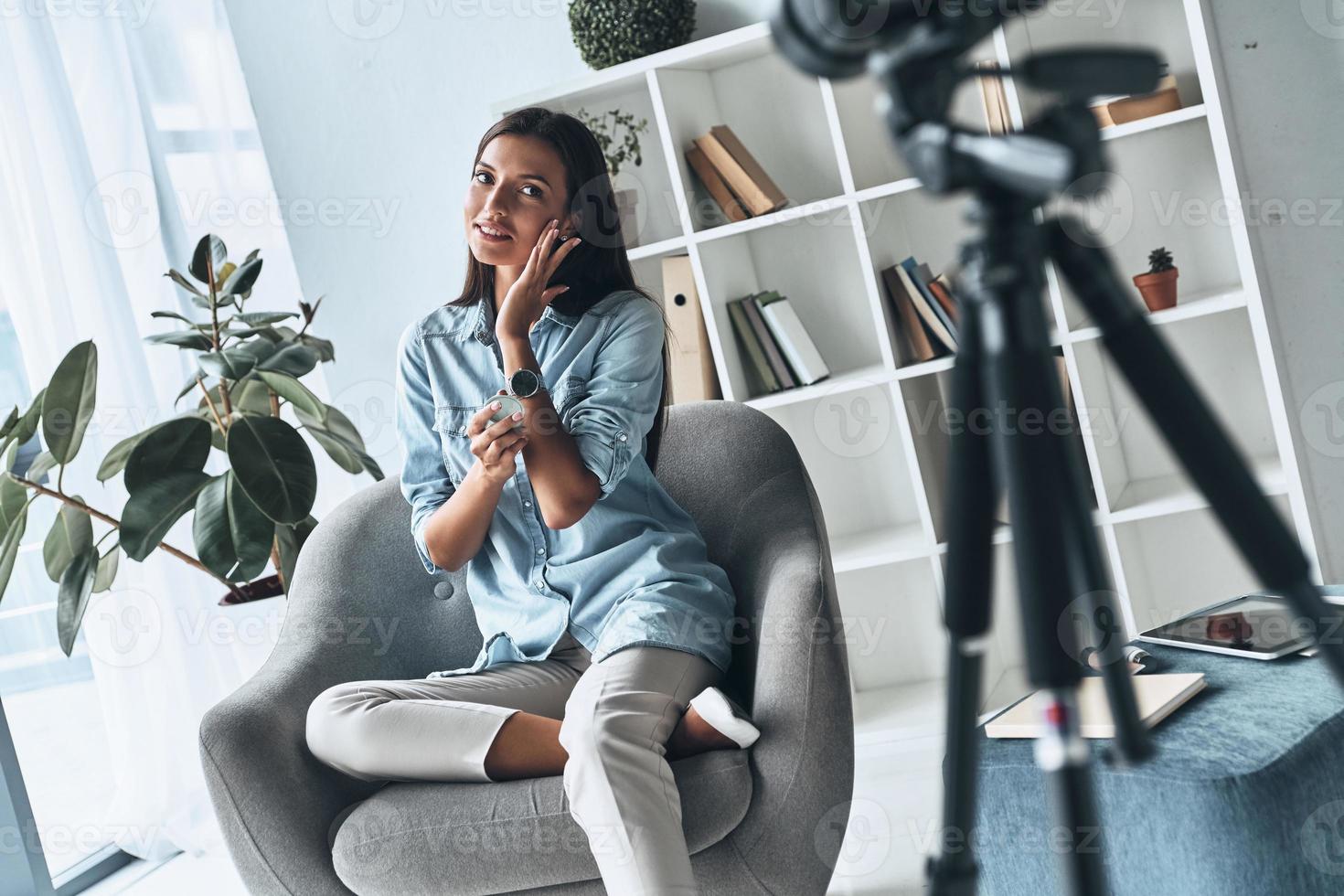 analisi bellezza Prodotto. attraente giovane donna l'applicazione nuovo cosmetici mentre fabbricazione nuovo video in casa foto