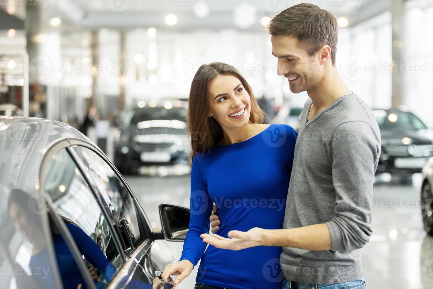 esso è il uno auto io volere bellissimo giovane coppia in piedi a il concessionaria la scelta il auto per acquistare foto