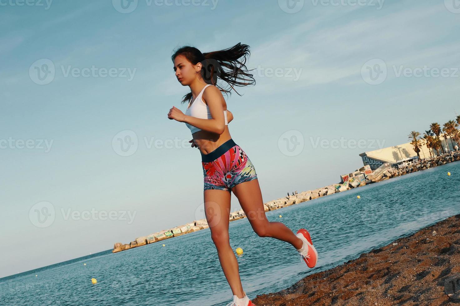 ogni giorno pieno con sport. attraente giovane donna nel gli sport capi di abbigliamento jogging mentre esercizio all'aperto foto