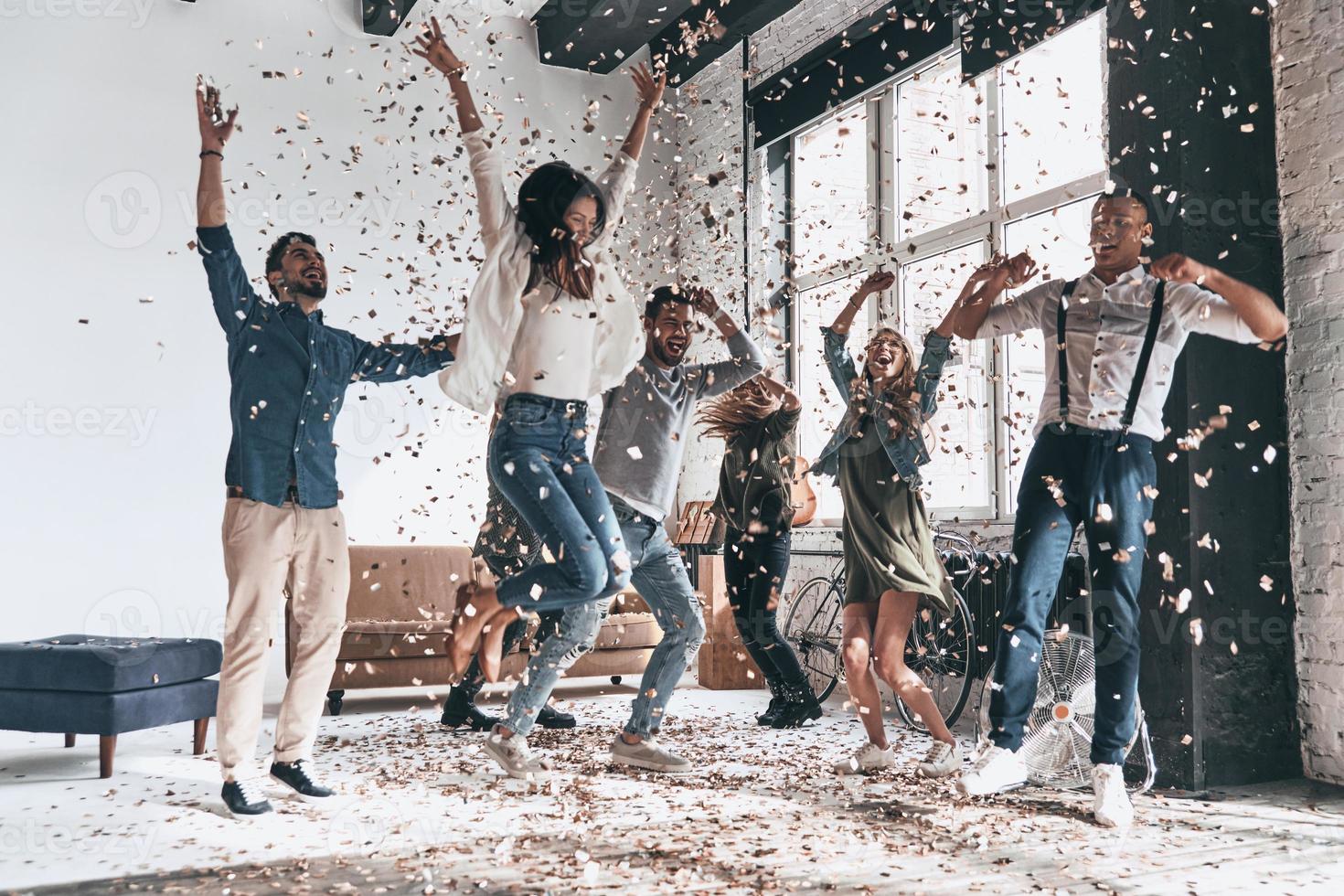 sospeso su insieme. pieno lunghezza di contento giovane persone danza mentre avendo un' festa con coriandoli volante ovunque foto