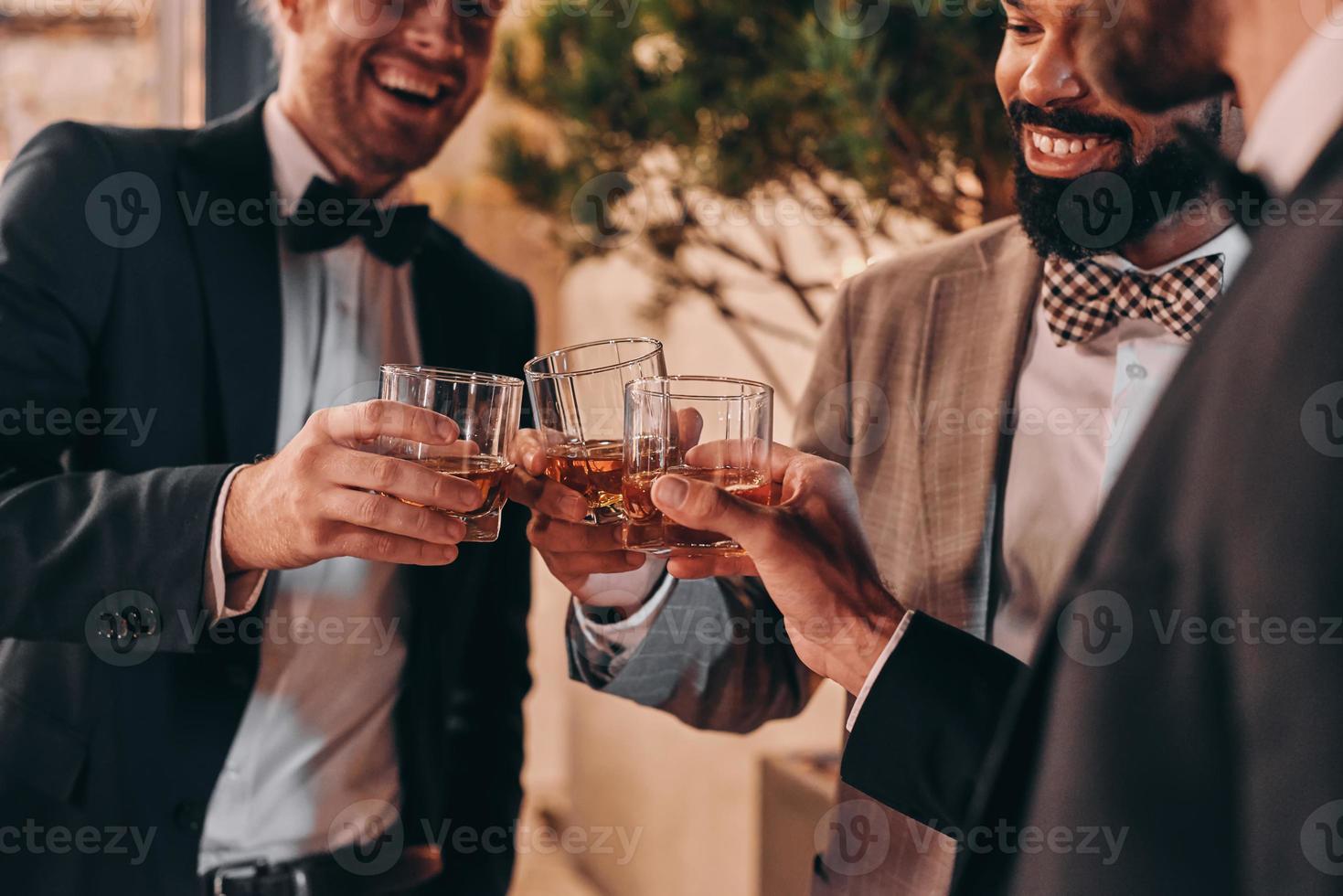 avvicinamento di tre ben vestito uomini potabile whisky e comunicare mentre la spesa tempo su festa foto