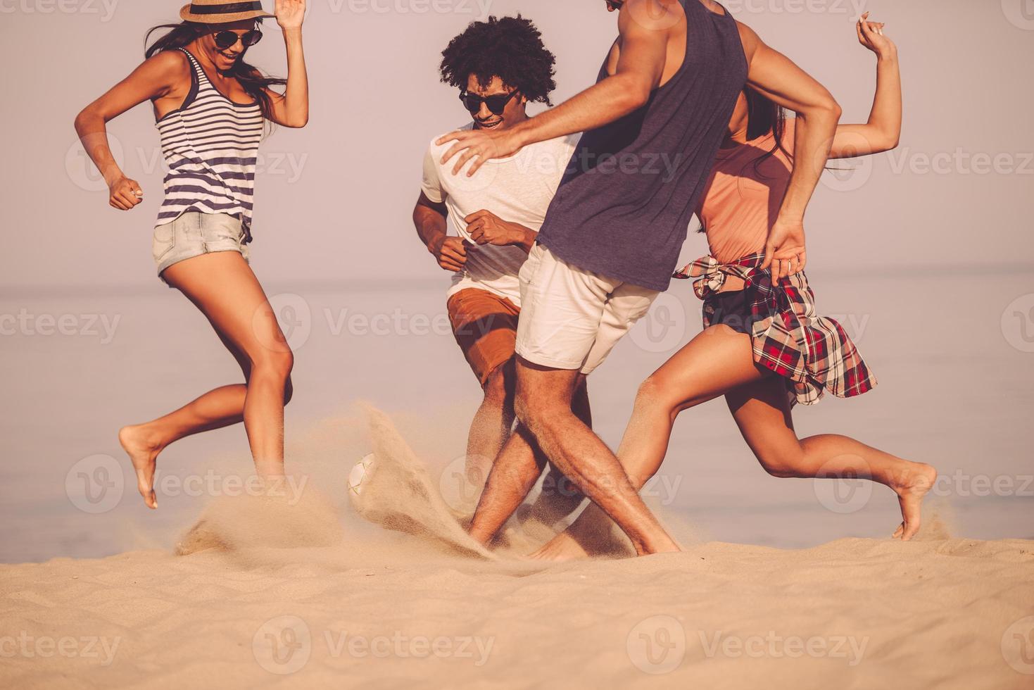 divertimento nel movimento. giovane allegro persone giocando con calcio palla su il spiaggia foto