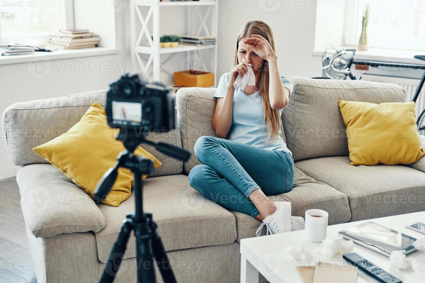 malato giovane donna soffiaggio naso mentre fabbricazione sociale media video a casa foto