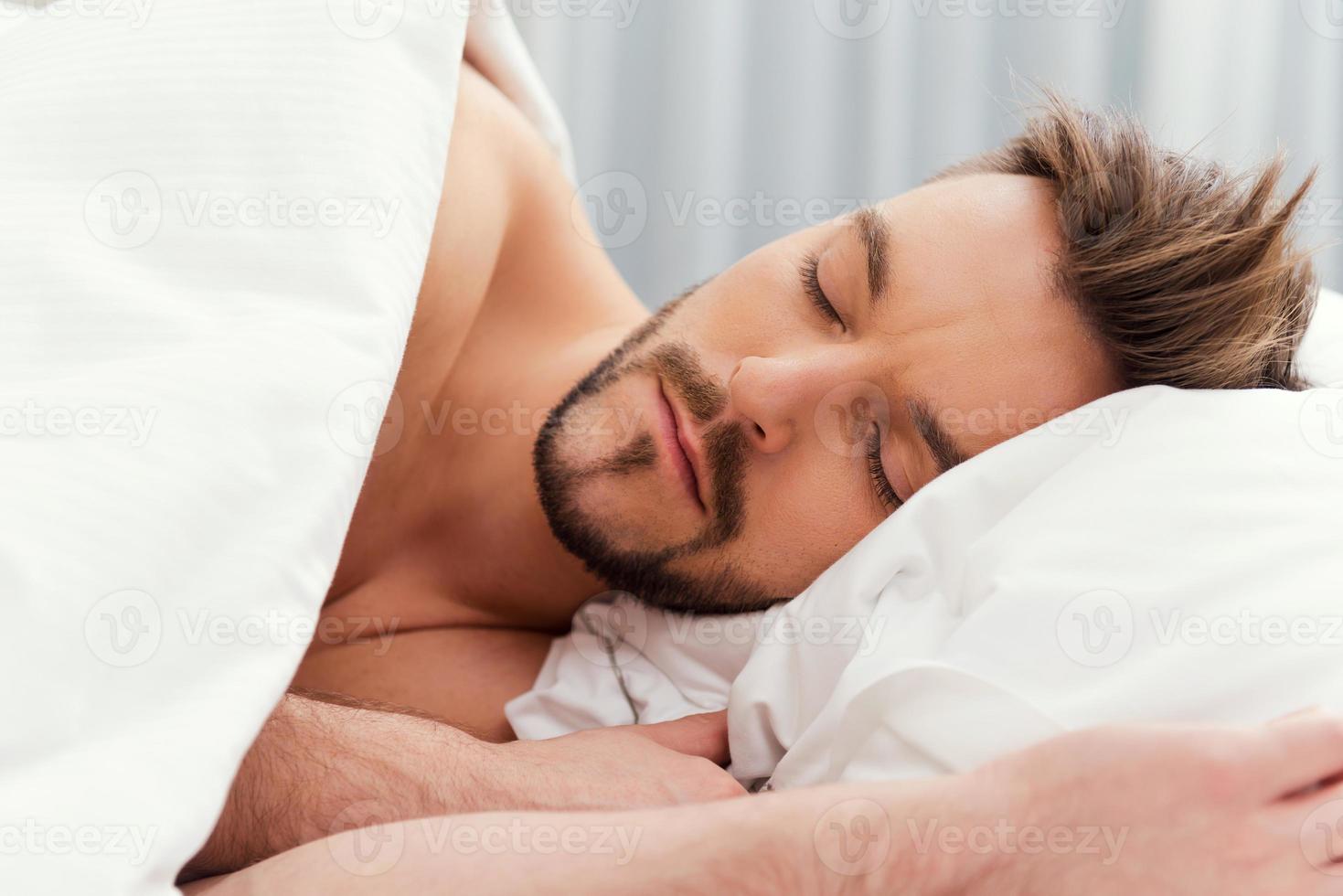 uomo dormendo. bello giovane A petto nudo uomo addormentato nel letto foto