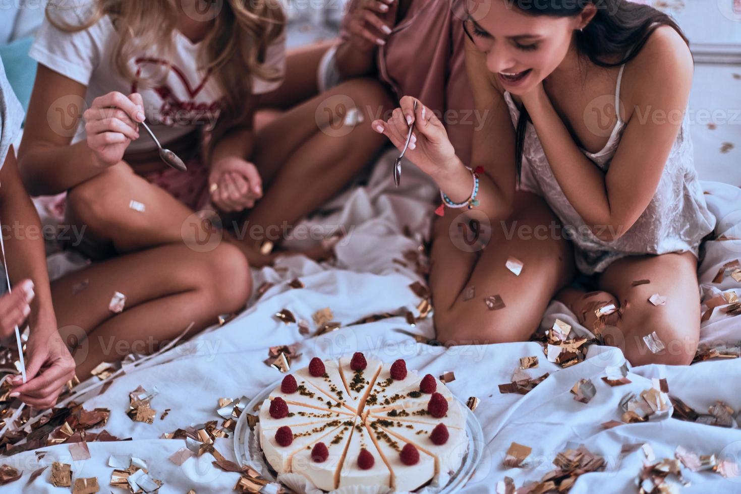 la scelta il migliore mordere. quattro giovane donne nel pigiama ottenere pronto per mangiare torta mentre avendo un' sonno festa foto