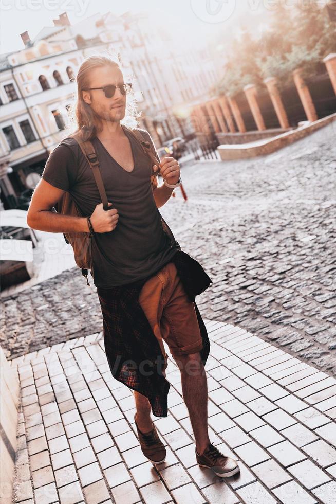estate viaggio. pieno lunghezza di giovane uomo nel casuale capi di abbigliamento vagare vuoto strada mentre a piedi all'aperto foto